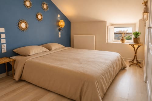 Chambre de la Maison Azur au Clos Divin avec lit king-size, mur bleu, miroirs en écailles dorées et vue sur la piscine