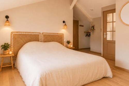 Chambre spacieuse du gîte Le Clos Divin avec tête de lit tissée, literie blanche, parquet et éclairage chaleureux