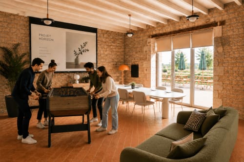 Quatre clients jouent au baby-foot dans le salon en pierre d'une chaumière avec vue sur la terrasse au Clos Divin, Doué-la-Fontaine