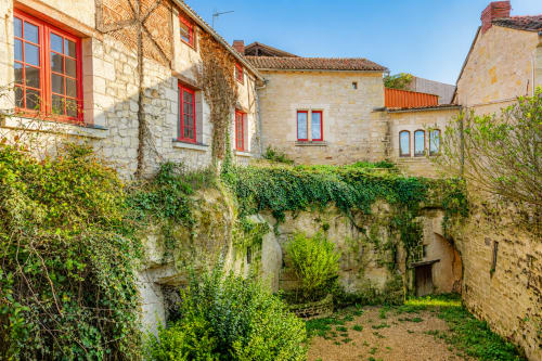 Cour de maison en pierre aux murs couverts de lierre et fenêtres rouges au Clos Divin, Doué-la-Fontaine