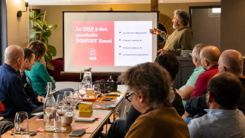 Présentation professionnelle à l'hôtel Le Clos Divin à Doué-la-Fontaine, France. Participants assis à une table consultant une diapositive sur