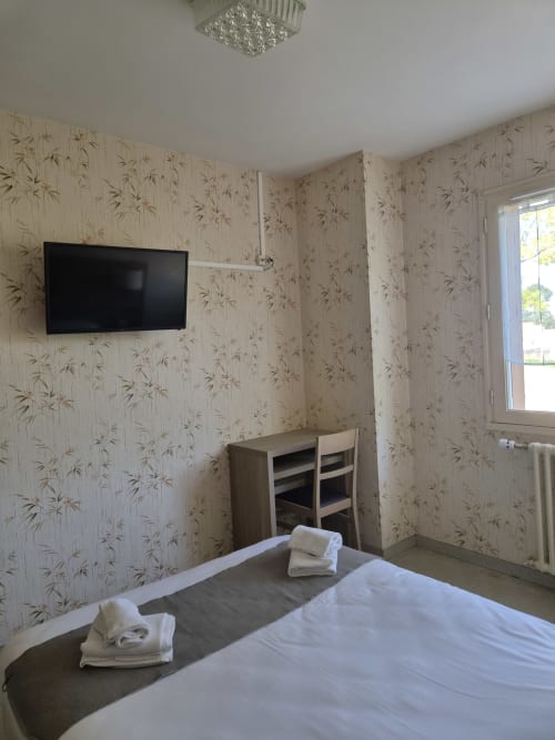 Chambre double à l'Hôtel Bar La Pinède à Saint-Jean-de-Monts avec papier peint, TV écran plat, lit et fenêtre