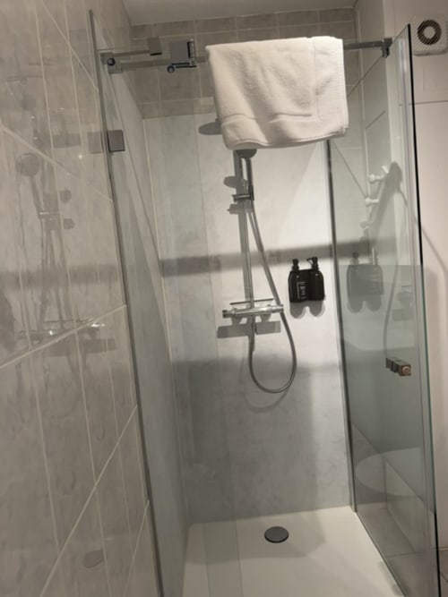 Moderne glazen douchewand met regendouchekop en witte handdoek in Studio Olive appartement bij L'arbre Qui Chante, Saint