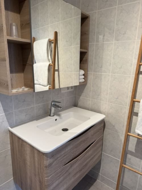 Moderne badkamer met witte wastafel, houten kast en verwarmd handdoekrek in B&B L'arbre Qui Chante