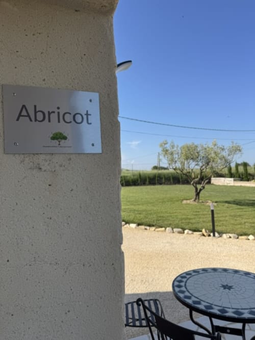 Bordje van de Abrikooskamer in L'arbre Qui Chante B&B in Saint Sauveur de Cruzières, met uitzicht vanaf balkon op groene velden en abrikozenboom