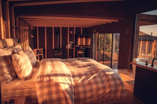 Luxury bedroom at Charm Nature B&B in Azóia with wooden beams, plaid bedding, and modern amenities bathed in golden sunlight
