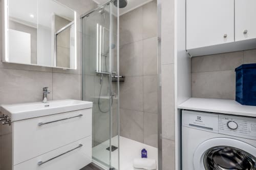 Salle de bain moderne à Riviera Home avec douche, meuble vasque blanc, lave-linge et miroir chauffant à Roquebrune-Cap