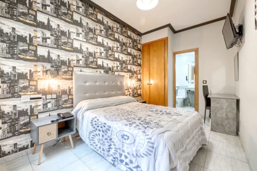 Moderno dormitorio doble en Hostal El Molino de Collado Villalba con papel pintado temático urbano, cabecero tapizado blanco y