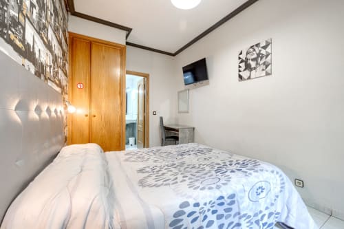 Habitación doble acogedora en Hostal El Molino, Collado Villalba, con cama, TV, escritorio y armario de madera