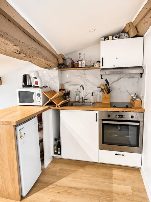Kitchenette moderne de l'appartement Le Petit Rochelois à ARLOÉ, La Rochelle avec armoires blanches, dosseret en marbre et bois