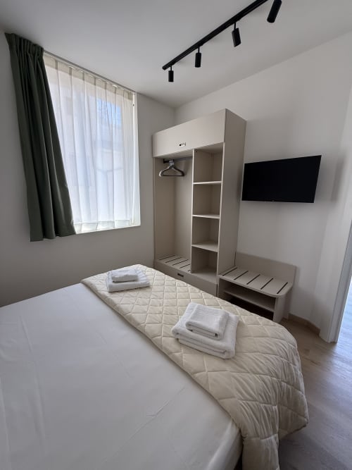 Modern bedroom at Residenza Sant'Antonio in Sottomarina with bed, wardrobe, TV, and window overlooking garden