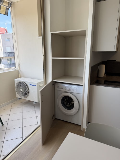Modern apartment laundry area with washing machine, storage shelves, AC unit, and window at Residenza Sant'Antonio,