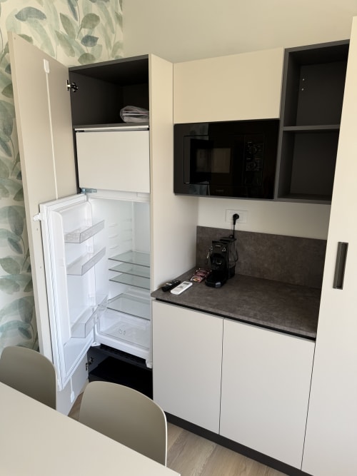 Modern kitchenette at Residenza Sant'Antonio with white cabinets, dark countertop, built-in microwave, and open refrigerator