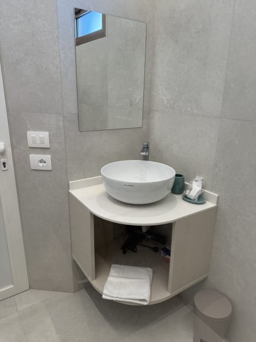Modern bathroom with round white vessel sink, mirror, and curved vanity at Residenza Sant'Antonio, Sottomarina