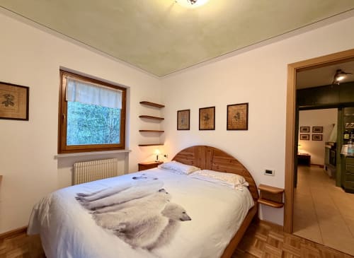 Camera da letto accogliente dell'appartamento CaseCasadei a Rocca Pietore con letto in legno, vista montagna e arredamento rustico