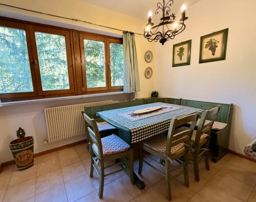 Zona pranzo dell'appartamento CaseCasadei con tavolo verde, sedie in legno e vista sulle montagne di Rocca Pietore