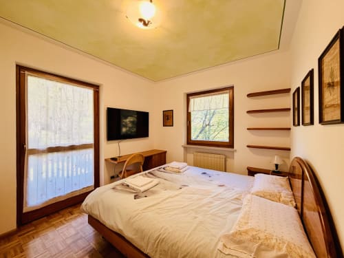 Luminosa camera da letto presso l'appartamento CaseCasadei a Rocca Pietore con vista montagna, TV e arredamento in legno