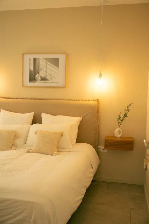 Chambre chaleureuse et épurée à La Maison du Potier B&B à Valras-Plage : literie crème, tableaux encadrés et luminaires suspendus