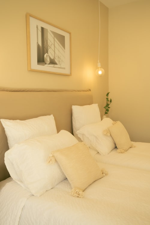 Chambre douillette à La Maison du Potier B&B à Valras-Plage avec literie crème, luminaire suspendu et tableaux encadrés
