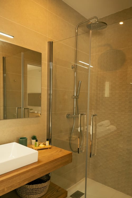Salle de bains moderne à La Maison du Potier avec douche à l'italienne, meuble vasque en bois et carrelage beige à Valras-Plage
