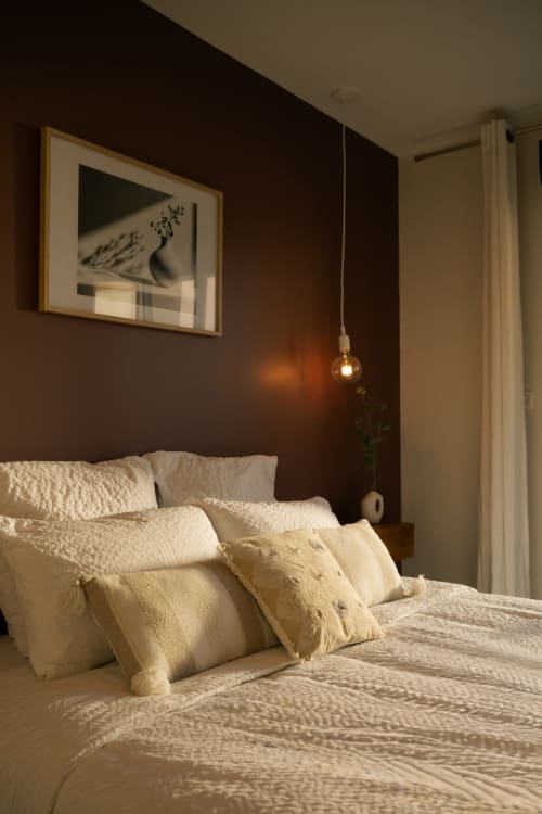 Cozy bedroom at La Maison du Potier B&B in Valras-Plage with cream bedding, dark accent wall, and pendant lighting