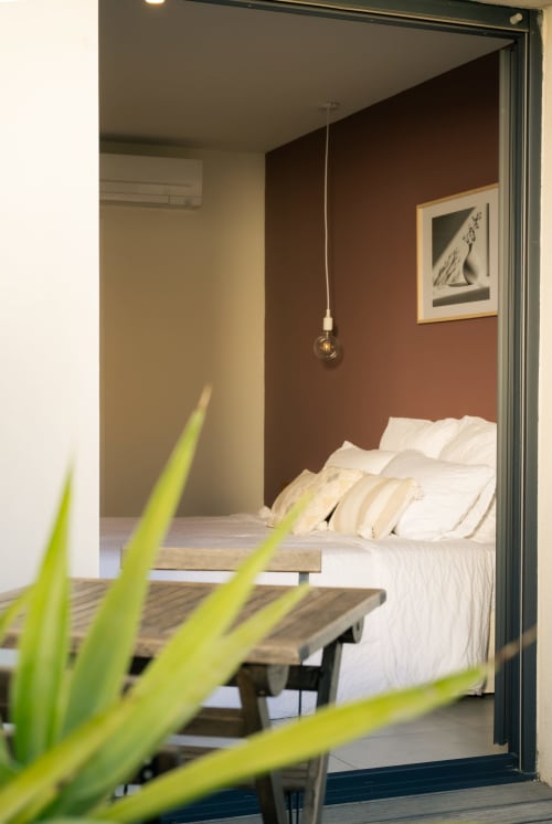 Bedroom at La Maison du Potier BnB in Valras-Plage with terracotta accent wall and white bedding