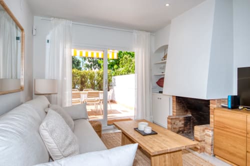 Bright living room with sofa, fireplace, and glass doors opening to sunny terrace in Palafrugell apartment