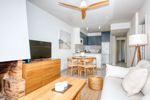 Modern open-plan apartment in Palafrugell with wooden furniture, kitchen, dining area, and comfortable living room seating.