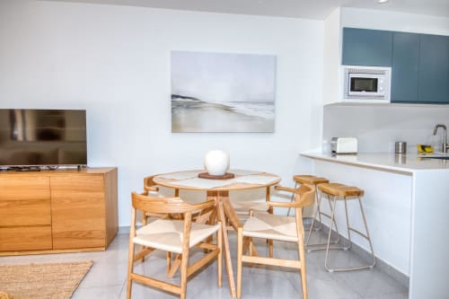 Modern apartment kitchen and dining area with wooden table, chairs, and bar seating in Palafrugell, Catalonia.
