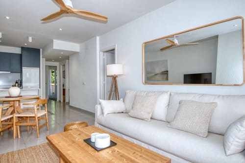Modern living room in Palafrugell apartment with white sofa, wooden furniture, and large mirror