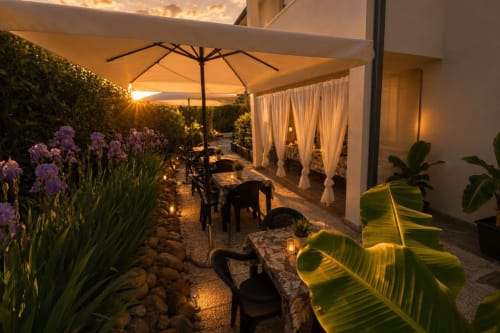 Patio serale del Gan Eden B&B con ombrellone, luci suggestive, fiori viola e tende bianche a San Benedetto del Querceto