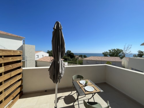 Terrazza sul tetto della Résidence Marina di Bravone con vista mare, tavolo da pranzo e ombrellone nero a Linguizzetta