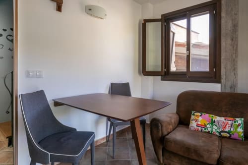 Sala de estar con comedor, sillas y sofá marrón en apartamento de Montgat con vistas a la montaña y gran ventanal