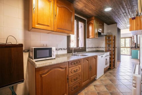 Cocina de madera con encimeras de granito, microondas y estufa en apartamento de Montgat con vistas a la montaña