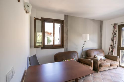 Luminoso salón con sillones de cuero, mesa de comedor y vistas a las montañas a través de la ventana en Front Beach Apartments, Montgat