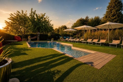 Area piscina di Gan Eden B&B a San Benedetto del Querceto con lettini, ombrelloni e vista sul giardino al tramonto