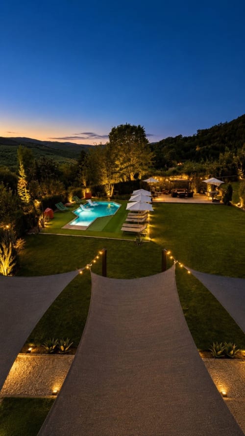 Giardino al crepuscolo di Gan Eden B&B con piscina illuminata, vialetto e colline toscane, San Benedetto del Querceto