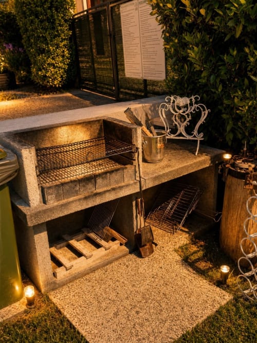 Elegante grill esterno presso il B&B Gan Eden a San Benedetto del Querceto con camino in pietra e illuminazione serale