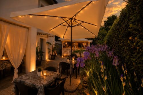 Terrazza serale di Gan Eden B&B con ombrellone, fiori viola e illuminazione calorosa a San Benedetto del Querceto