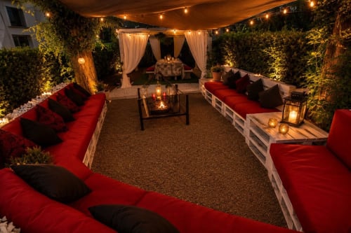 Gan Eden lussuosa lounge esterna con sedute rosse, luci decorative e giardino elegante a San Benedetto del
