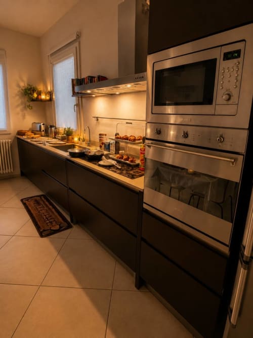 Cucina moderna del Gan Eden B&B con elettrodomestici in acciaio inossidabile, pensili scuri e illuminazione calda a San Benedetto del