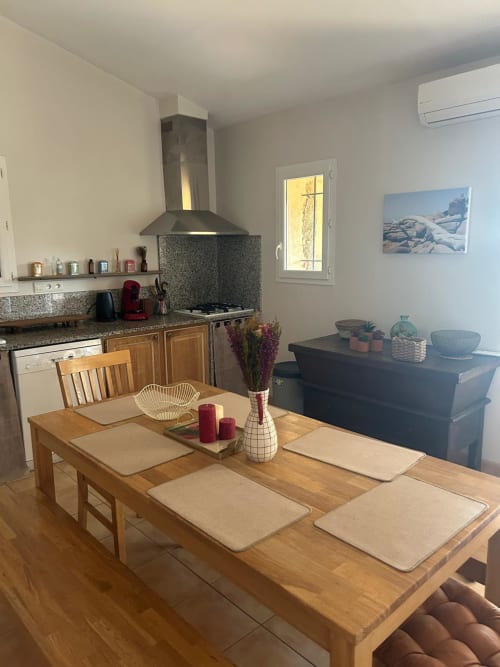 Cuisine-séjour moderne à Vista D'oro à Monacia d'Aullène avec table en bois, plan de travail en granit et vue sur la mer
