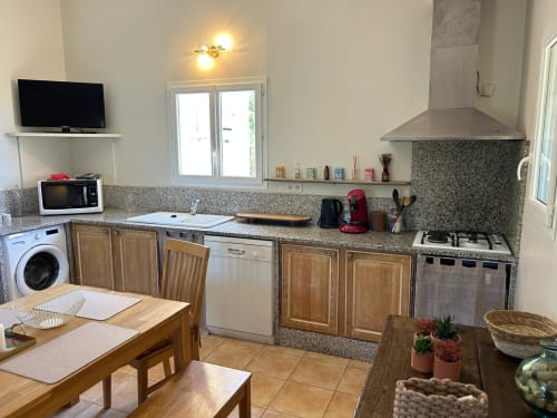 Cuisine moderne de l'appartement Vista D'oro, Monacia d'Aullène, avec comptoirs en granit, armoires en bois et acier inoxydable