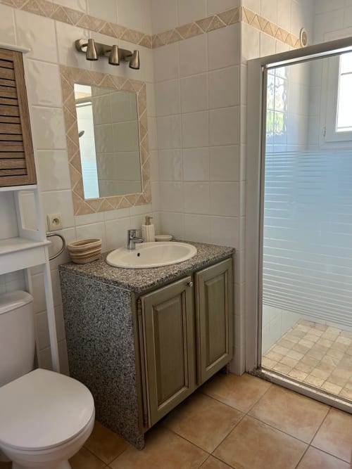 Salle de bain moderne de la chambre Vista D'oro avec meuble-lavabo en granit, murs carrelés blancs, miroir encadré et douche ouverte à Monacia