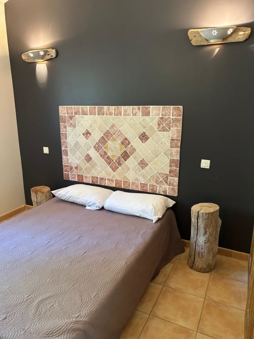 Chambre moderne à Vista D'oro avec tête de lit carrelée, oreillers blancs, murs sombres, accents de bois rustique et appliques murales