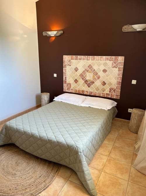 Chambre de l'hôtel Vista D'oro à Monacia d'Aullène avec lit, tête de lit en carrelage décoratif et mur d'accent marron