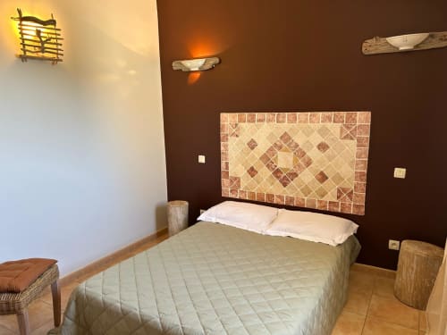 Chambre moderne à Vista D'oro avec tête de lit en carrelage décoratif, oreillers blancs, literie beige et murs d'accent marron chaud