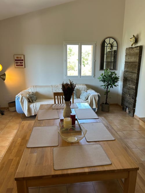 Salle à manger Vista D'oro avec table en bois, couverts, canapé crème et vue sur Monacia d'Aullène, Corse