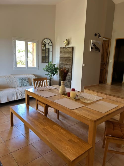 Salle à manger lumineuse de Vista D'oro à Monacia d'Aullène avec table en bois, bancs et baies vitrées vue sur la mer
