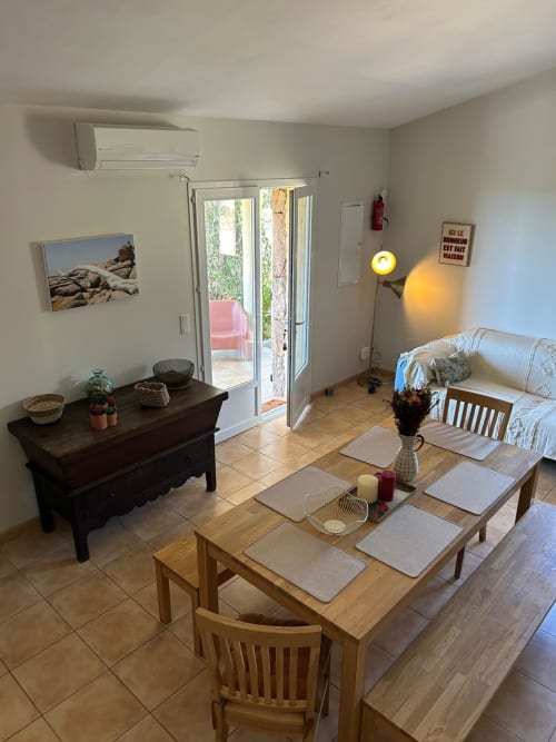 Séjour lumineux avec table à manger, canapé et commode en bois foncé à Vista D'oro en Corse